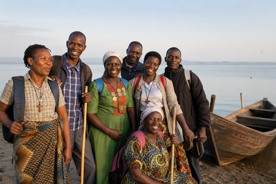 Entebbe Lake Pilgrims gathered by a lakeshore boat in morning light
